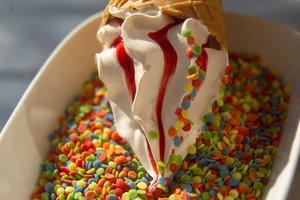 Soft ice cream being decorated with colourful sprinkles