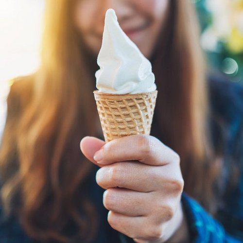 Woman holding waffle containing white soft ice cream in her hand